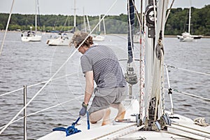 Man on sailboat tying a rope to mooring ball