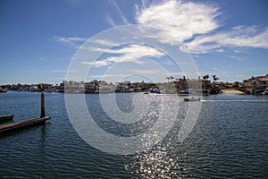 A man sailing a small motor boat at Huntington Harbour with boats and yachts docked in Huntington Harbour and homes