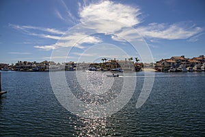 A man sailing a small motor boat at Huntington Harbour with boats and yachts docked in Huntington Harbour and homes