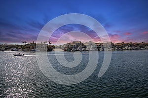 A man sailing a small motor boat at Huntington Harbour with boats and yachts docked in Huntington Harbour and homes