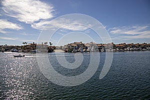 A man sailing a small motor boat at Huntington Harbour with boats and yachts docked in Huntington Harbour and homes