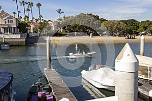 A man sailing a small motor boat at Huntington Harbour with boats and yachts docked in Huntington Harbour and homes