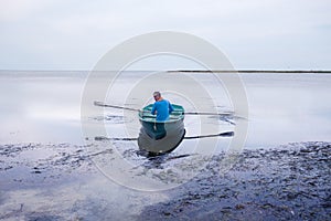 Man sailing on a small rowing boat along the sea coast