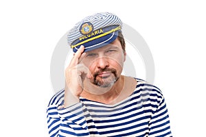 A man sailor in a cap with a smoking pipe in front of a white ba