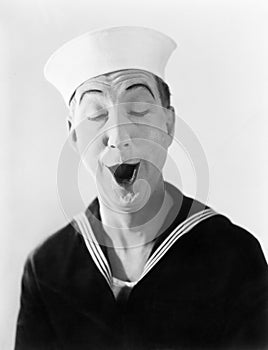 Man in sailor hat and uniform making a silly pantomime face