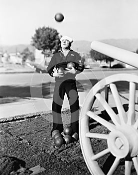 Man in sailors uniform trying to juggle cannon balls photo