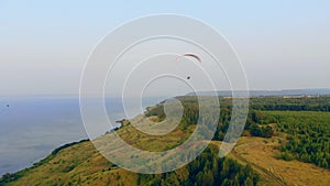Man sailplanes a big paraglider over fields. Paraglider in sky.