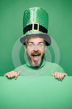 Man in Saint Patrick`s Day leprechaun party hat having fun on green background. Banner or card.