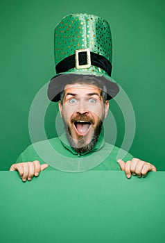 Man in Saint Patrick's Day leprechaun party hat having fun on green background. Banner or card. photo