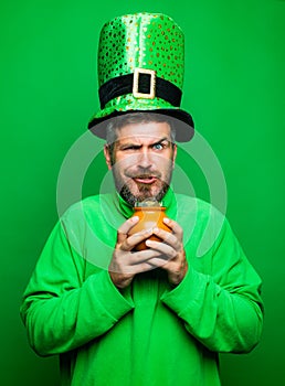 Man in Saint Patrick`s Day leprechaun party hat hold Pot of gold on green background. Happy St Patricks Day concept with