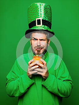 Man in Saint Patrick's Day leprechaun party hat hold Pot of gold on green background. Happy St Patricks Day concept