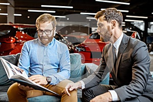 Man with sales manager on the couch at the car showroom