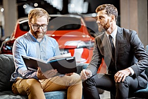 Man with sales manager on the couch at the car showroom