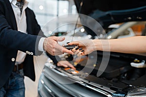 Man and salesgirl choosing auto in car dealership