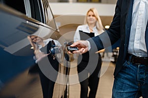 Man and saleswoman choosing auto in car dealership