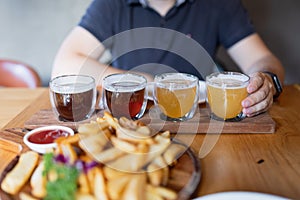 Man sampling variety of seasonal craft beer in pub. Beer samplers in small glasses individually placed in holes