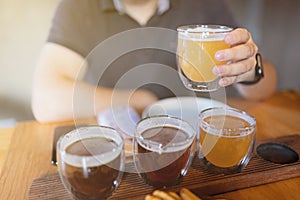 Man sampling variety of seasonal craft beer in pub. Beer samplers in small glasses individually placed in holes