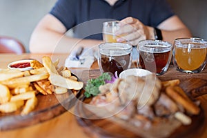 Man sampling variety of seasonal craft beer in pub. Beer samplers in small glasses individually placed in holes