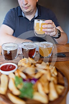Man sampling variety of seasonal craft beer in pub. Beer samplers in small glasses individually placed in holes