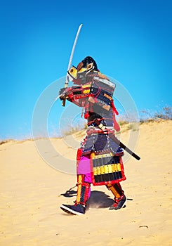 Man in samurai costume with sword running on the sand. Men in sa