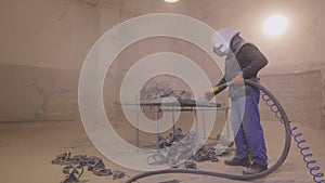 The man is sandblasting the detail. Sandblast metal parts. Sandblasting gun