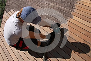 Man sanding and cleaning wooden deck with the power sander