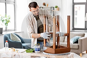 man sanding old round wooden table with sponge