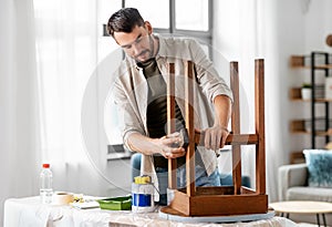 man sanding old round wooden table with sponge