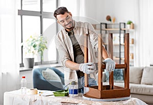 man sanding old round wooden table with sponge