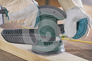 Man sanding a wood with orbital sander