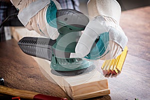 Man sanding a wood with orbital sander