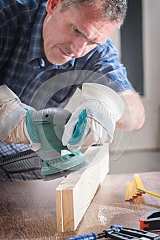 Man sanding a wood with orbital sander