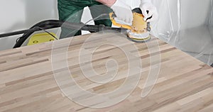 Man sanding wood with orbital sander in workshop