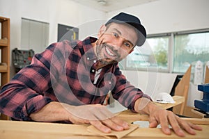 man sanding wood with sander in workshop