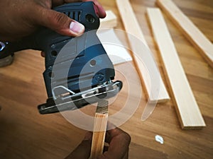 Man sanding wood with square sander in a workshop.