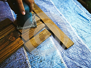 Man sanding wood with square sander in a workshop.