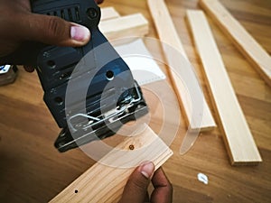 Man sanding wood with square sander in a workshop.