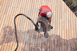 Man sanding wood terrace on the sun with orbital power sander top view