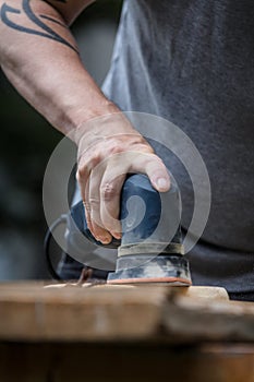 Man is sanding a wooden plank