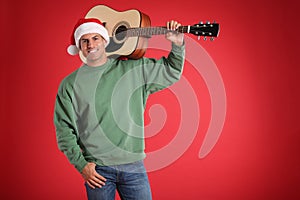 Man in Santa hat with acoustic guitar on red background, space for text. Christmas music
