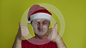 Man in Santa hat makes gesture with thumbs of both hands.