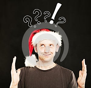 Man in Santa Hat showing his Hands with question marks above his head. Sale Concept