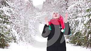 man in santa's scarf and cap in winter forest or park, snowy cold weather before christmas, holding gift box in