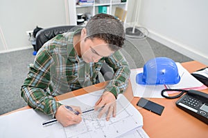 Man sat at desk working on blueprints