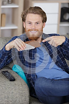 man sat on sofa pointing at bar chocolate