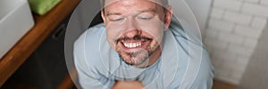 Man with satisfied smile sits on toilet