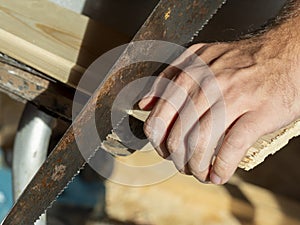 A man is sawing a board with a hand saw. Woodworking concept. Close-up