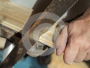 A man is sawing a board with a hand saw. Woodworking concept. Close-up