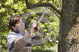 Man sawing a branch with an handsaw photo