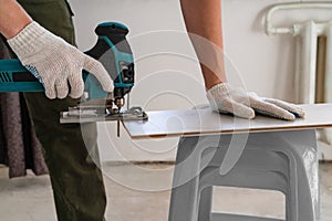 Man sawing laminate. Man is repairing the floor in the house, laminate flooring in the style of old boards